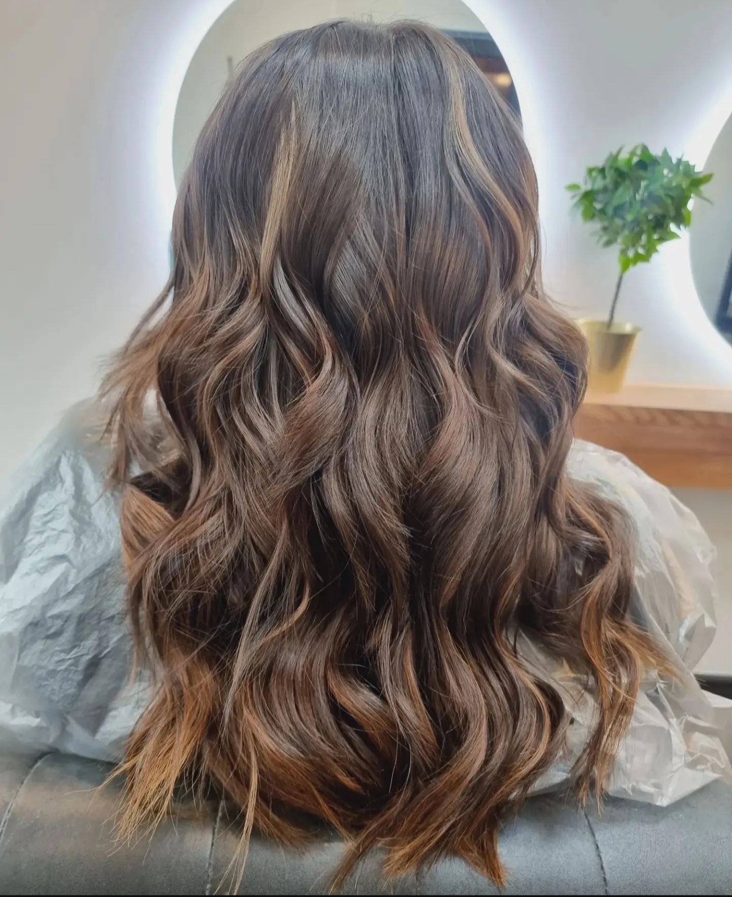 Back view of voluminous wavy hair with dimensional caramel highlights at TONES Salon