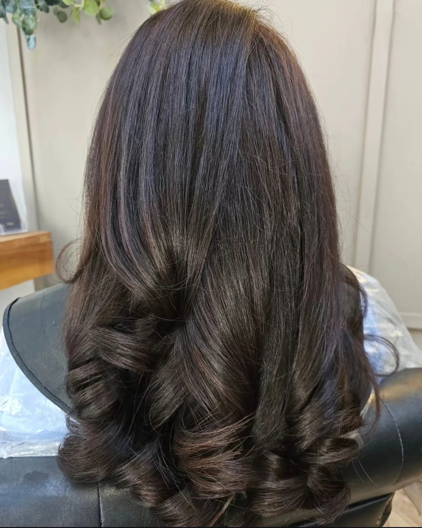 Back view of dark brown hair with soft waves and polished curled ends styled at TONES