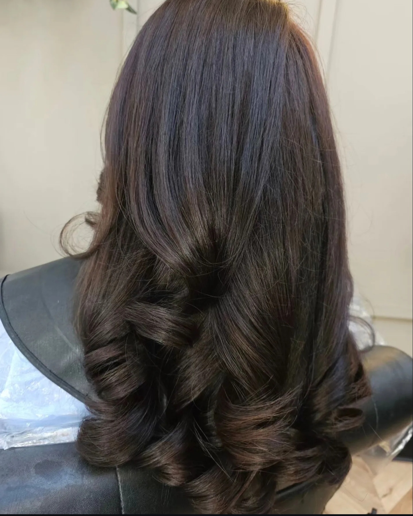 Back view of long, dark hair styled in loose, flowing curls at TONES Hair & Beauty Salon in Lahore